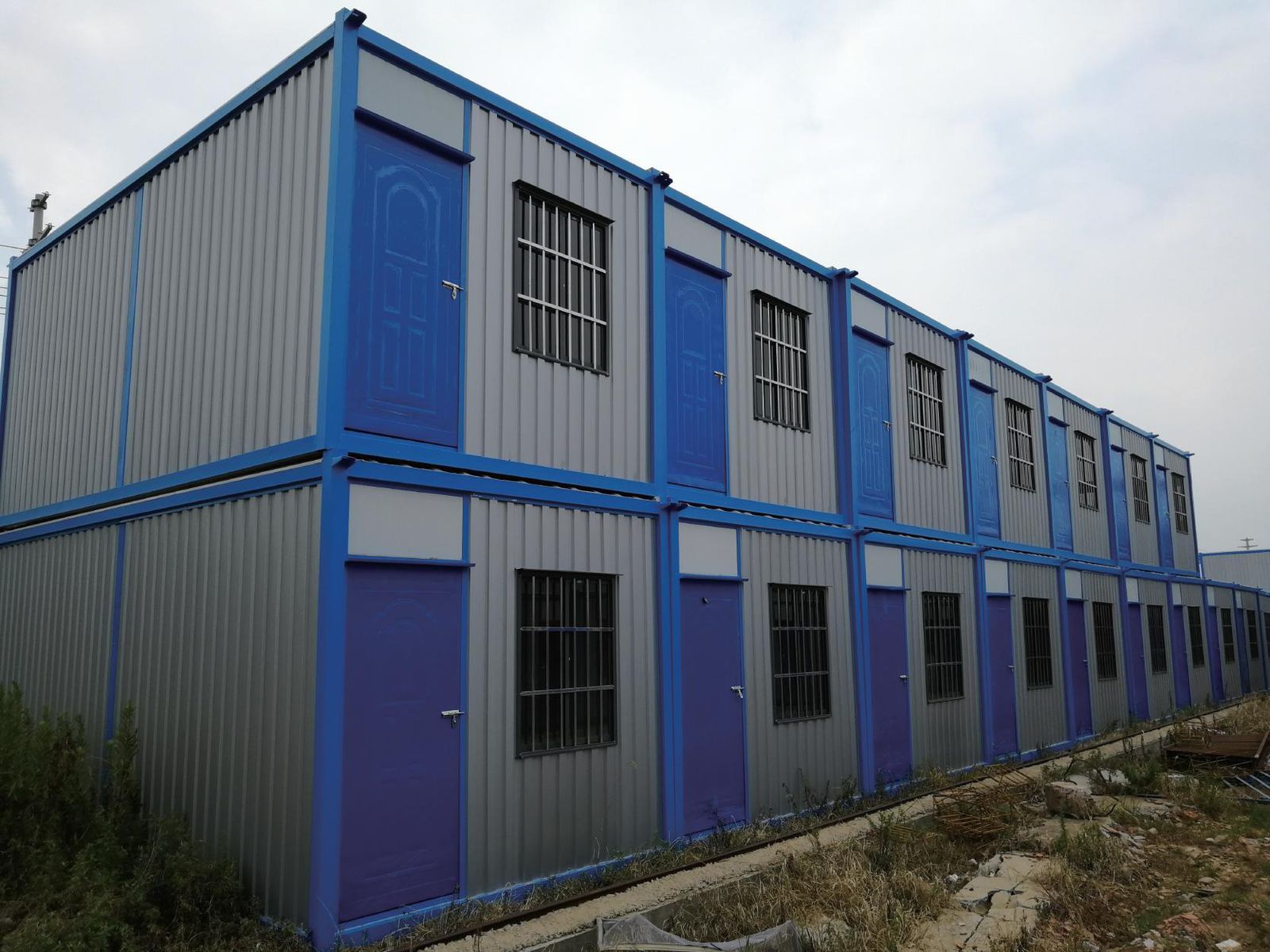 Row of prefabricated site camp dormitory units with blue frames