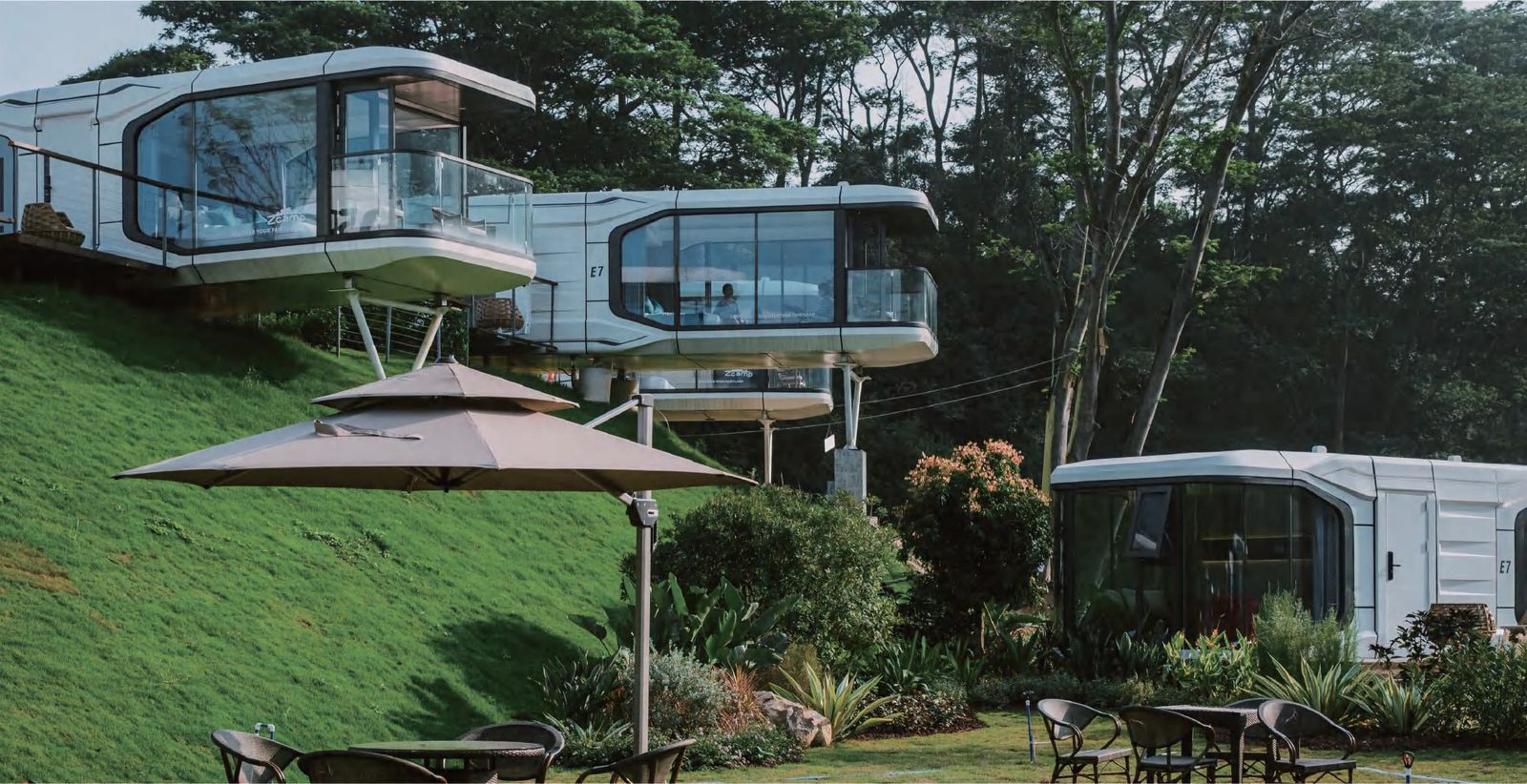 Capsule houses on wooden deck hillside with outdoor seating