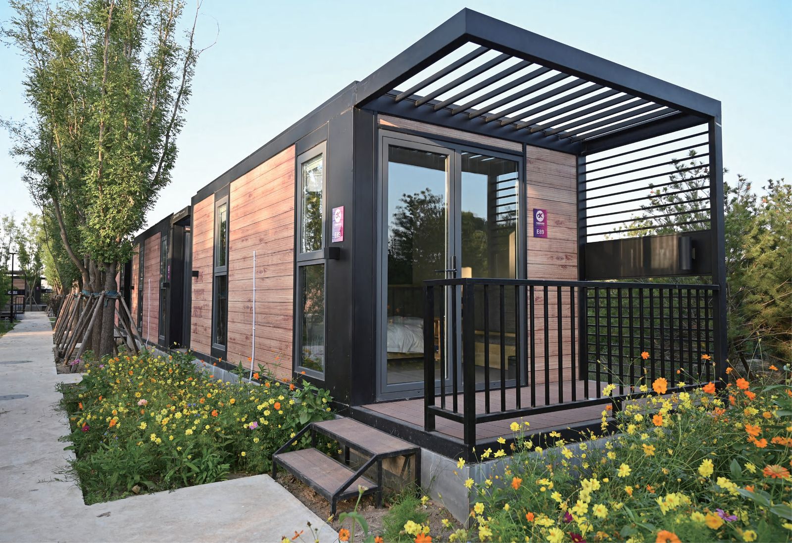 Modern prefab villa with wood-grain siding and black metal frame